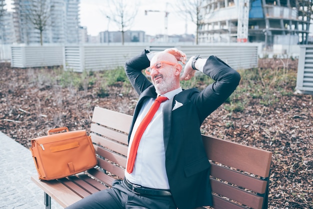 Middle aged businessman outdoor stretching sitting bench