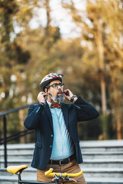 A middle-aged businessman putting helmet on his head and go to work by bicycle.