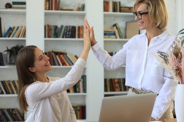 Middle aged businesswoman giving high five to her young female collegue.