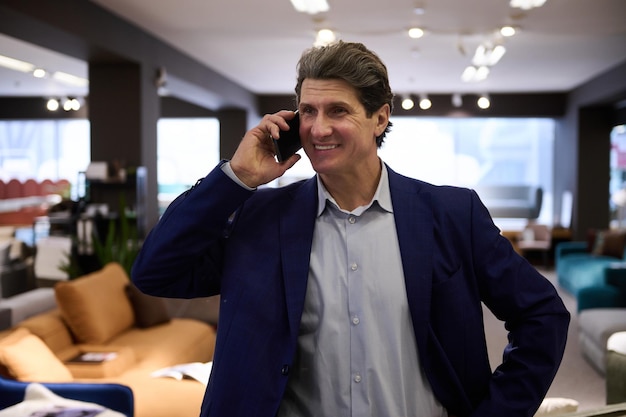 Middle aged Caucasian man talking on mobile phone while visiting a furniture store