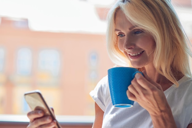 Donna caucasica di mezza età con tazza e smartphone