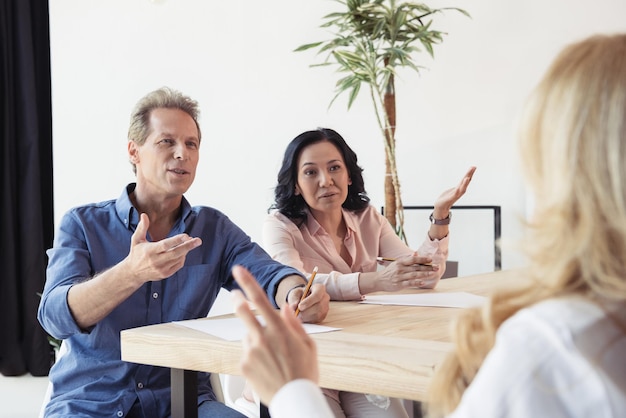 Коллеги среднего возраста спорят на деловой встрече в офисе