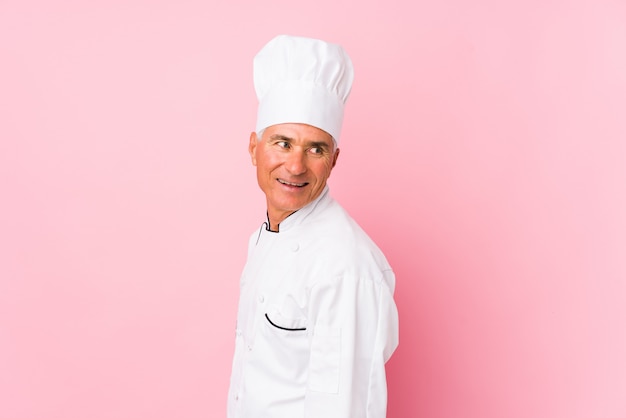 Middle aged cook man isolated looks aside smiling, cheerful and pleasant.