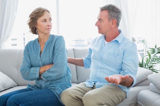 Middle aged couple sitting on the sofa having a dispute