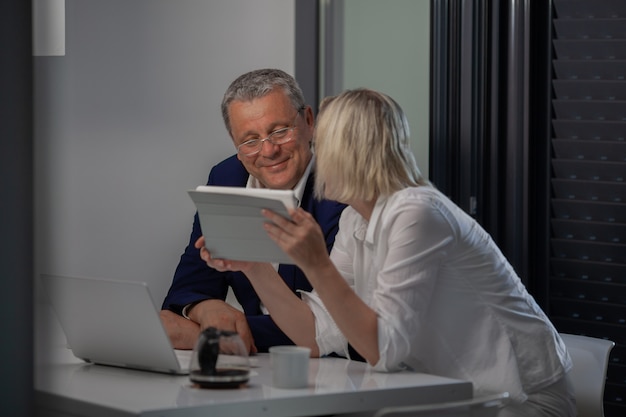 A middle aged couple at the table with their devices