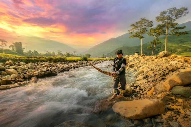 Middle aged farmer Playing a musical instrument By the edge of the stream in the countryside In the north of Vietnam