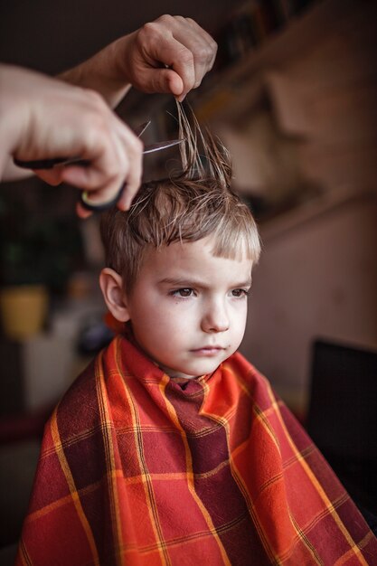 Photo middle aged father cutting hair to his little son by himself at home