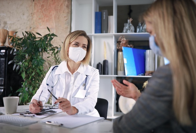 Middle aged female doctor therapist in consultation with patient in office.