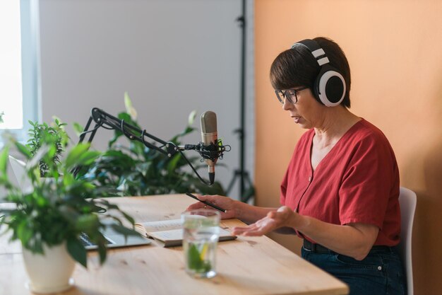 Middle-aged female radio presenter talking into the microphone and reading news - radio broadcast online concept person