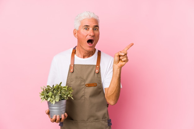 Middle aged gardener man isolated pointing to the side