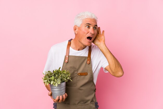 Middle aged gardener man isolated trying to listening a gossip.