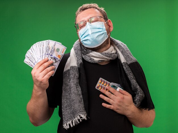 Больной мужчина средних лет в медицинской маске и шарфе изолирован на зеленой стене