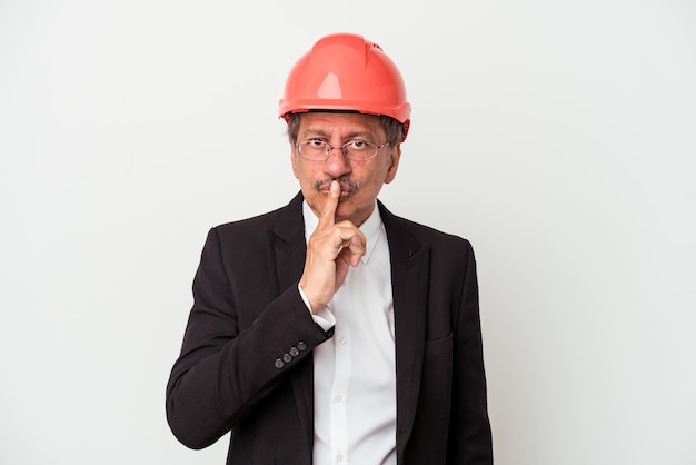 Middle aged indian architect man isolated on white background keeping a secret or asking for silence.