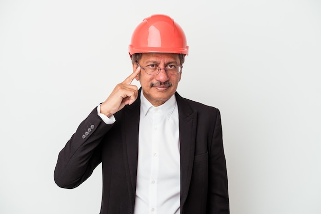 Middle aged indian architect man isolated on white background pointing temple with finger, thinking, focused on a task.