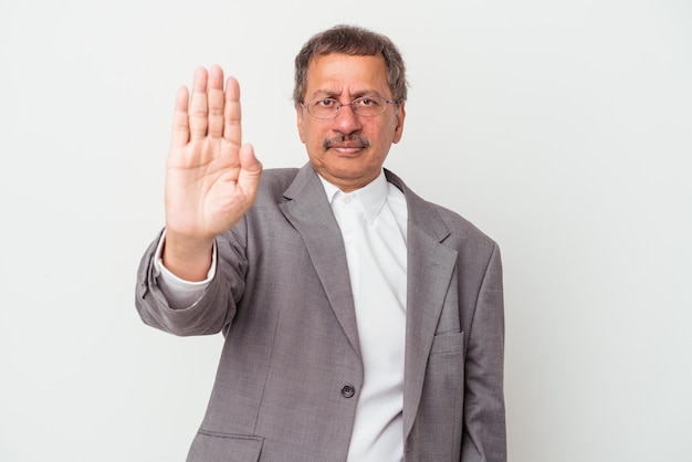 Middle aged indian business man isolated on white background standing with outstretched hand showing stop sign, preventing you.