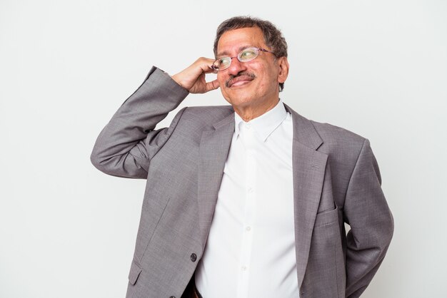 Middle aged indian business man isolated on white background touching back of head, thinking and making a choice.