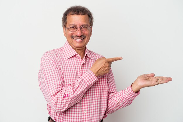 Middle aged indian man isolated on white background excited holding a copy space on palm.