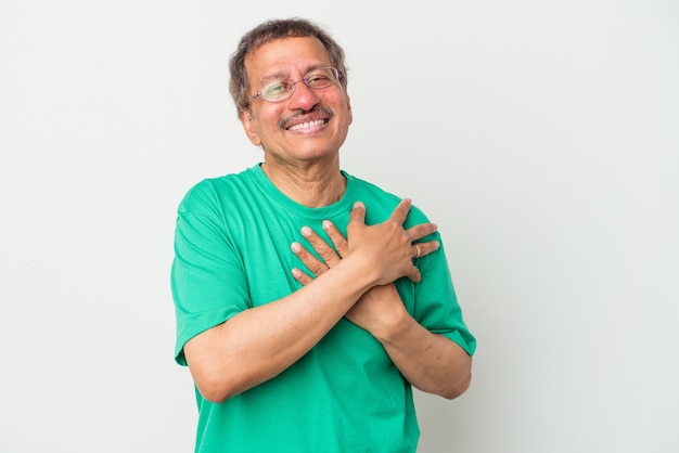 Middle aged indian man isolated on white background has friendly expression, pressing palm to chest. Love concept.