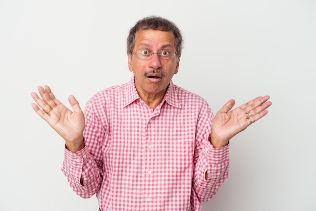 Middle aged indian man isolated on white background surprised and shocked.