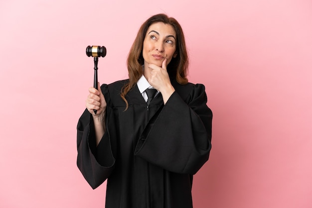 Photo middle aged judge woman isolated on pink background having doubts