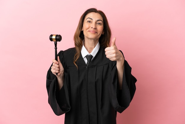 Middle aged judge woman isolated on pink background with thumbs up because something good has happened