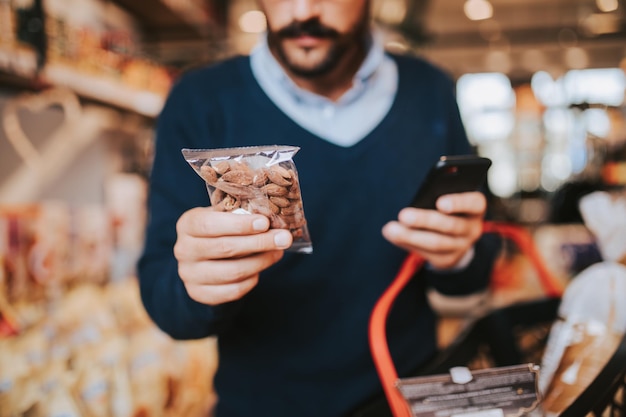 現代のスーパーマーケットで健康的な食べ物や飲み物を買う中年の男性。