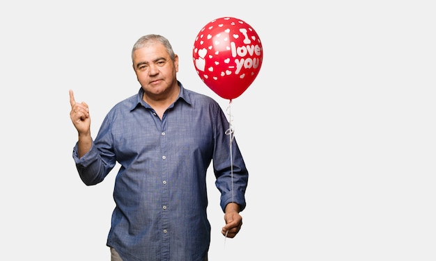 Человек средних лет, празднующий День святого Валентина, указывающий на сторону с пальцем