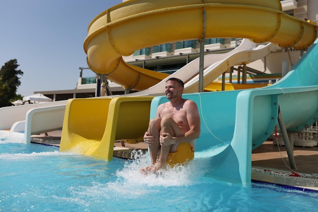 Middle aged man having fun sliding at water park summer vacation