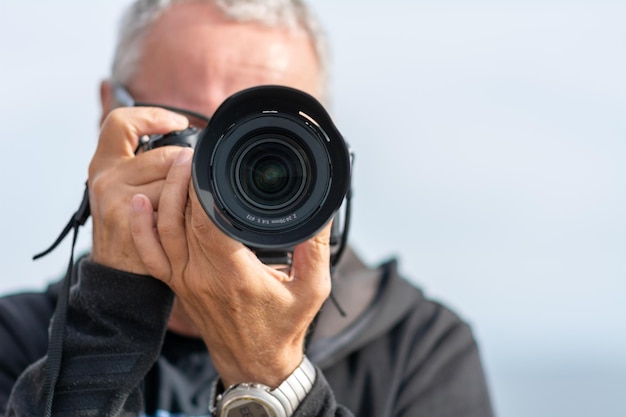 Photo a middle-aged man in his 50s taket a picture with a modern mirrorless camera