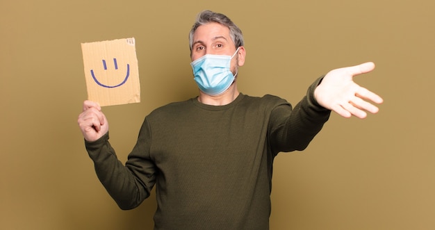 Middle aged man holding happy board with a protective mask