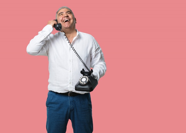 Middle aged man laughing out loud, having fun with the conversation, calling a friend or a client