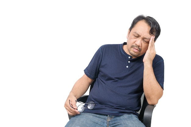 Uomo di mezza età seduto su una sedia e sensazione di stress e mal di testa isolato su sfondo bianco. problema e concetto di assistenza sanitaria.