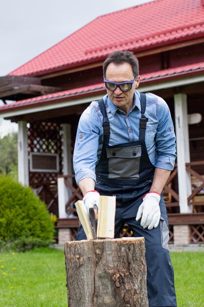 Middle-aged man wearing goggles chopping wood