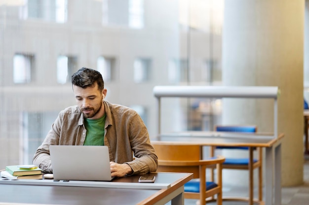 Middle aged man in wireless earphones sitting at desk using laptop workplace Studying online