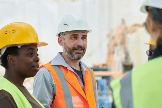 Dirigente di mezza età di una squadra di lavoratori della cava di marmo che parla con i subordinati