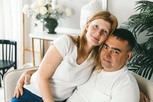 Photo middle-aged married couple hugging on the couch