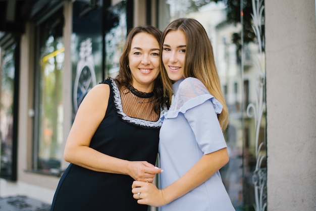 Middle-aged mother and adult daughter hug each other and smile