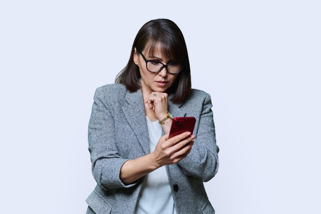 Middle aged serious business woman looking in smartphone