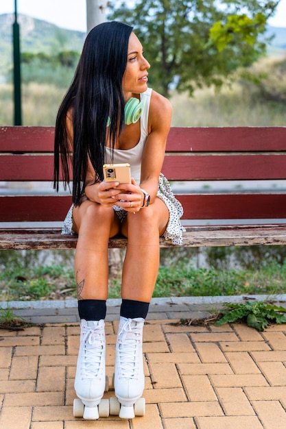 Middle aged skater woman with roller skates sitting on a bench