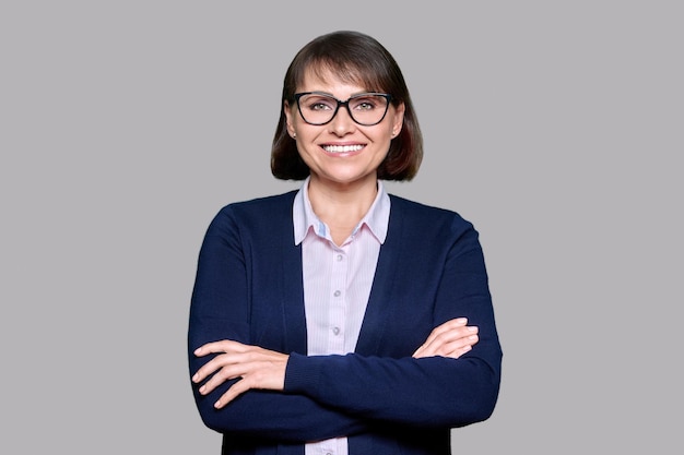 Middle aged smiling business woman over gray isolated background