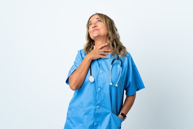 Middle aged surgeon woman over isolated wall looking up while smiling