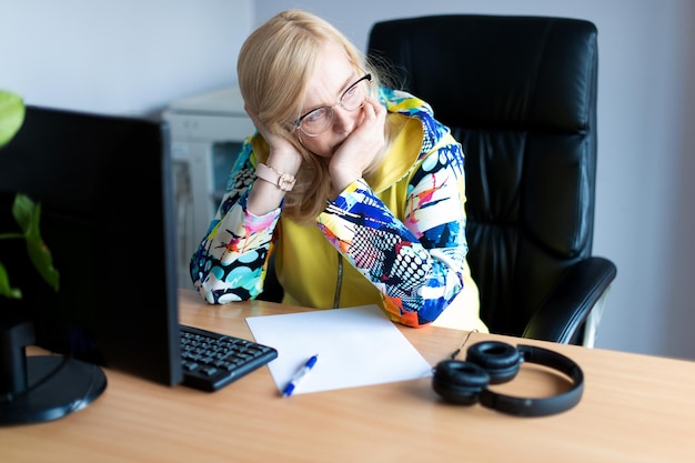 Donna d'affari stressata e frustrata stanca di mezza età che lavora disperata in ufficio con il computer