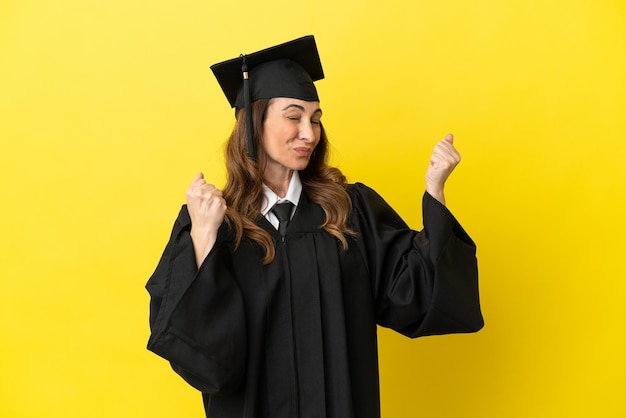 Middle aged university graduate isolated on yellow background celebrating a victory