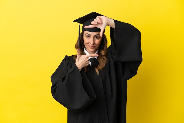 Middle aged university graduate isolated on yellow background focusing face. Framing symbol