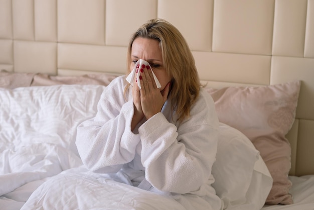 ベッドにいる中年女性は気分が悪く、風邪をひいている