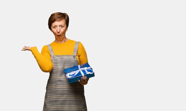 Middle aged woman celebrating valentines day holding something on palm hand