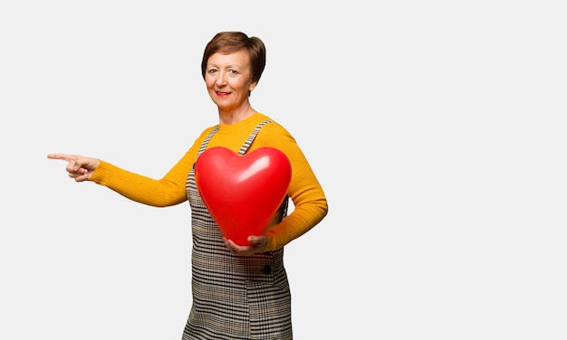 Middle aged woman celebrating valentines day pointing to the side with finger