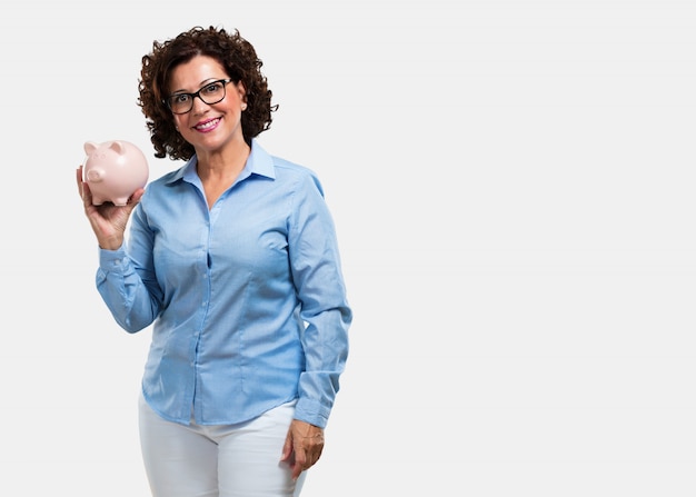 Middle aged woman confident and cheerful, holding a piglet bank and being quiet because the money is saved