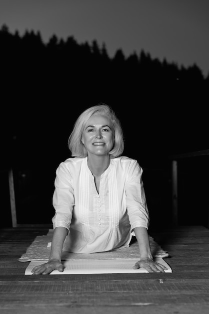 middle aged woman doing yoga outdoors in forest