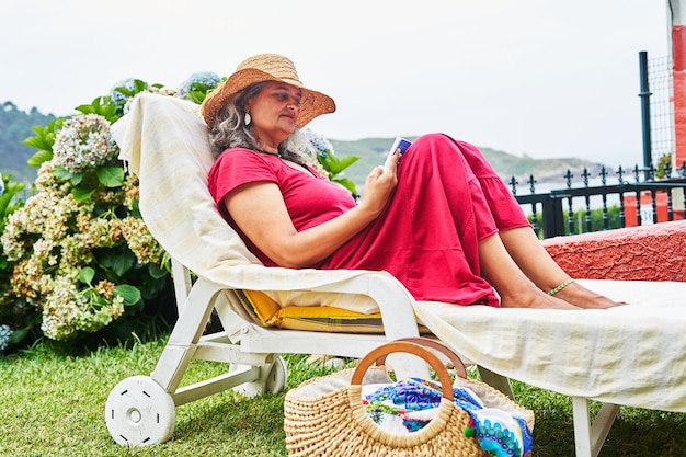 Middle aged woman in dress reading on a deck chair